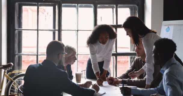 Mentore africano focalizzato che insegna a diversi team aziendali che lavorano su documenti — Video Stock