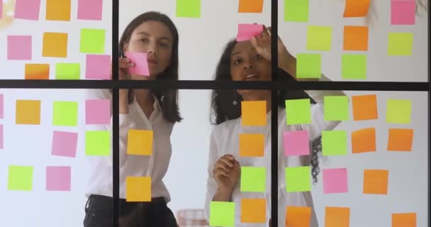 Diversos colegas trabalhando juntos escrevem ideias em notas pegajosas — Vídeo de Stock