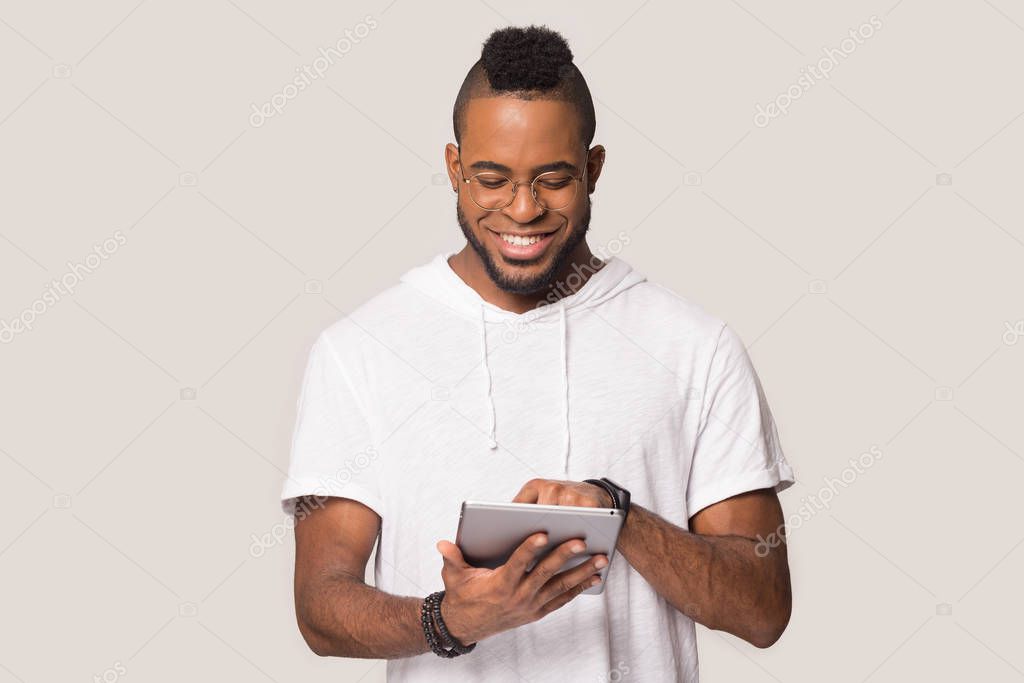 Happy black man using tablet shopping online in studio