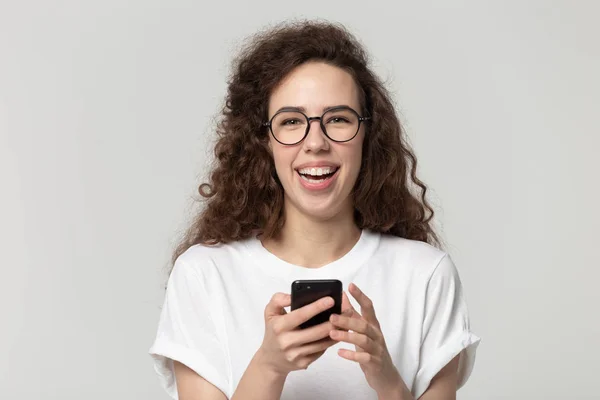 Zblízka mladá šťastná žena v brýlích drží smartphone. — Stock fotografie