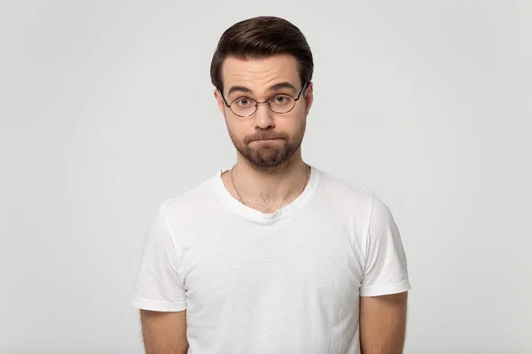 Millennial dissatisfied serious bearded man in eyeglasses squeezing lips. — Stock Photo, Image