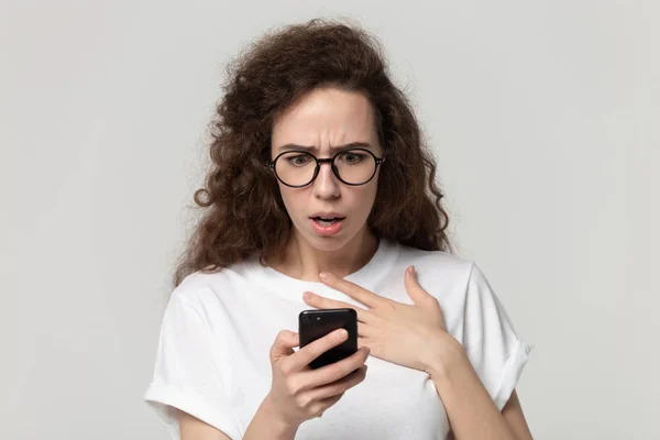 Asustada mujer milenaria preocupada mirando la pantalla del dispositivo . — Foto de Stock