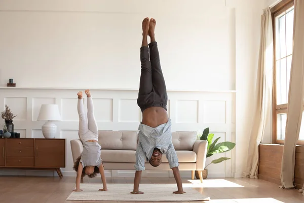 African father and daughter stand on hands heads down position — ストック写真