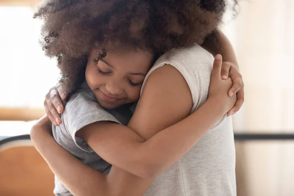 African daughter closed eyes snuggled up to mother hugged her — ストック写真