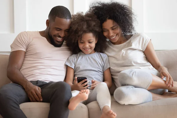 Famille africaine assis sur le canapé s'amuser en utilisant des applications smartphone — Photo