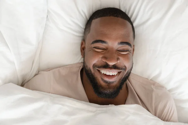 Vista de cima ri cara afro bonito deitado na cama — Fotografia de Stock