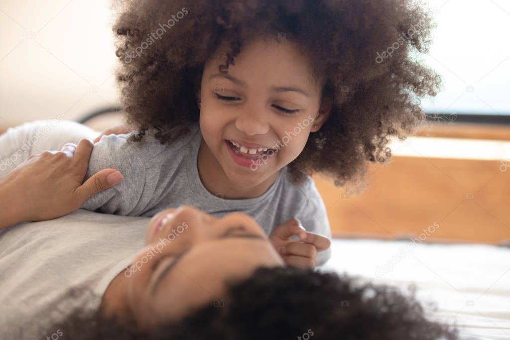 African mother and daughter lying in bed playing enjoy pastime