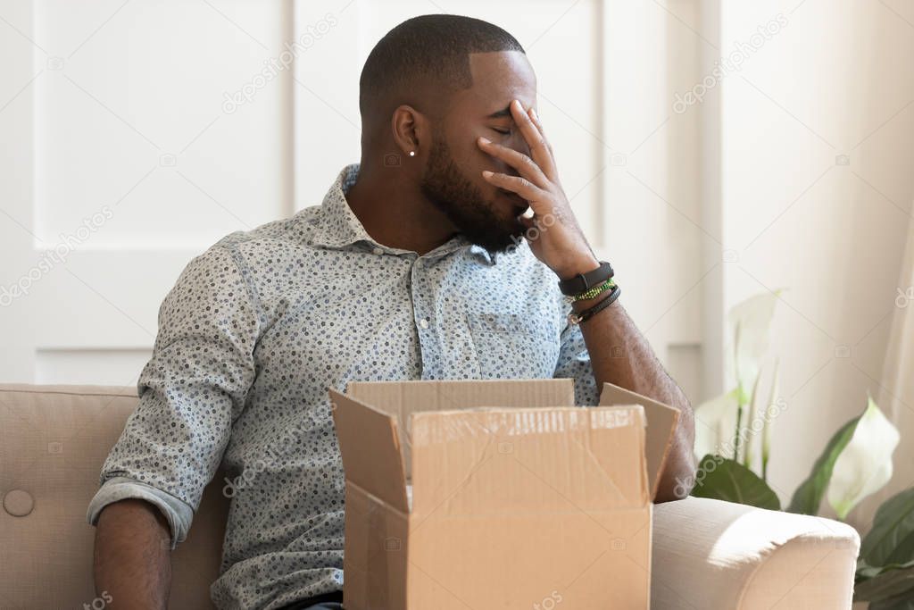 African guy feels stressed saw that goods in parcel damaged