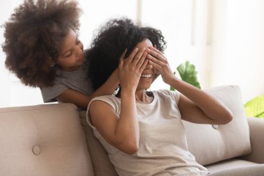 Kızın elleri kapalı. Annenin gözleri kapalı. Kapalı mekanda oynuyor.