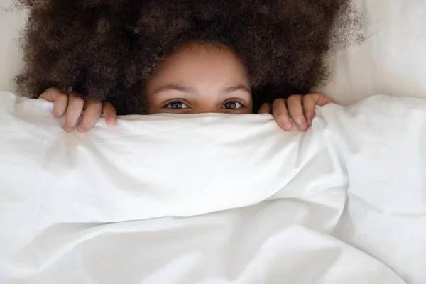 Gadis african kecil yang lucu bersembunyi di balik selimut menatap kamera — Stok Foto