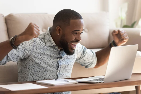 Emocionado hombre africano leer el mensaje en la computadora celebrando la oportunidad recibida —  Fotos de Stock