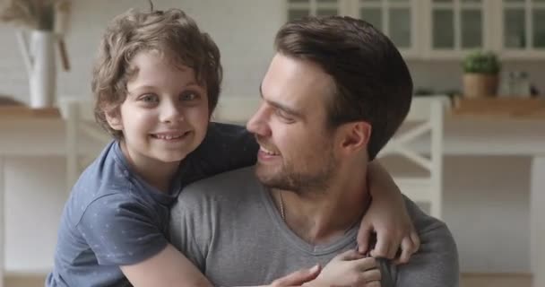 Strzał w głowę szczęśliwy mały chłopiec przytulający uśmiechniętego ojca. — Wideo stockowe