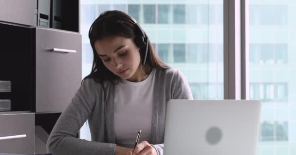 Gemotiveerde vrouw met een hoofdtelefoon, studeert online op kantoor. — Stockvideo