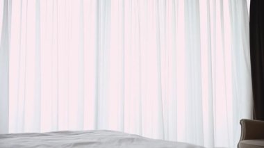 Smiling attractive brunette woman opening curtains lace.