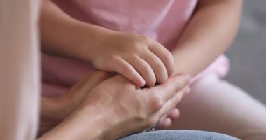 Close up affectionate mother holding hands of little preschool daughter.