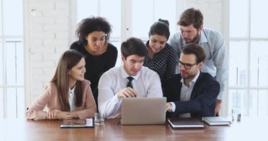 Diverse ethnicity employees group discussing digital data on laptop