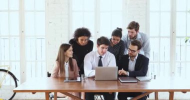 Business team of six brainstorm gather in office with laptop