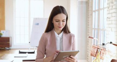 Happy millennial businesswoman professional using digital tablet standing in office