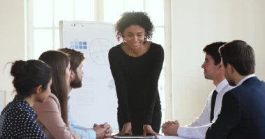 Gülümseyen Afrikalı kadın patron toplantıda çok ırklı bir ekiple konuşuyor.