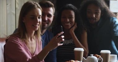 Smiling caucasian woman holding mobile phone, taking selfie with friends.