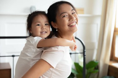 Genç Asyalı anne küçük melez kızıyla oynuyor.