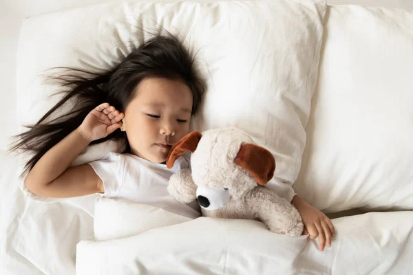 Pequeña chica asiática dormir en la cama con juguete esponjoso — Foto de Stock