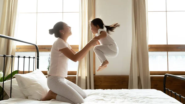 Веселая молодая мама и маленькая дочь играют дома — стоковое фото