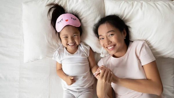 Overjoyed asiatico giovane mamma e piccola figlia sdraiata a letto — Foto Stock