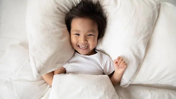 Overjoyed asiático pequeña chica despertar en casa cama — Foto de Stock