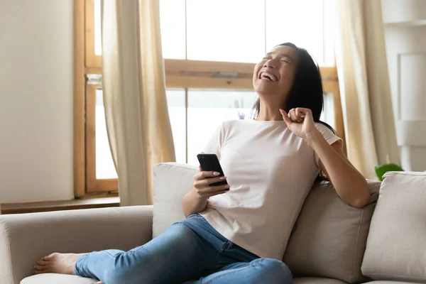 Nadšení asijské ženy bavit pomocí mobilu doma — Stock fotografie