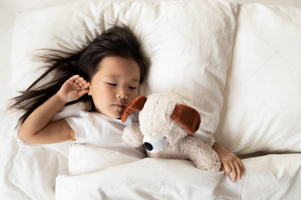 Small Asian girl sleep in bed with fluffy toy