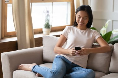 Gülümseyen Asyalı kız modern akıllı telefonlarda internete göz atıyor