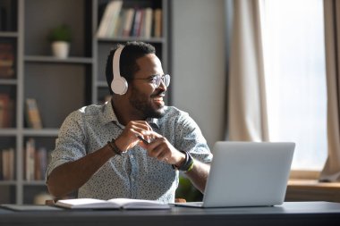 Mutlu Milenyum Afrikalı işadamı ofiste müzik dinlerken kulaklık takıyor.