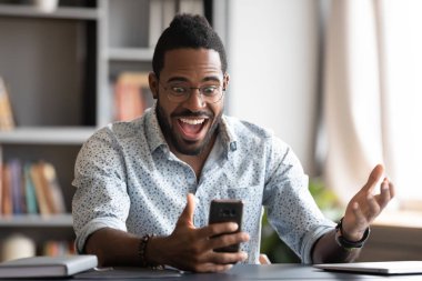 Çok neşeli Afrikalı iş adamı akıllı telefon kullanıyor. Mobil kazanma konusunda heyecanlı.