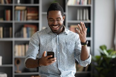 Heyecanlı mutlu Afrikalı işadamı, akıllı telefondan iyi haberleri okuyarak kutluyor.