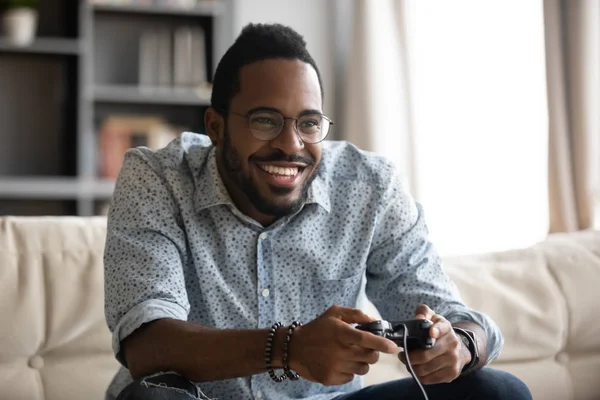 Feliz chico africano joven sosteniendo controlador de joystick jugando videojuego —  Fotos de Stock