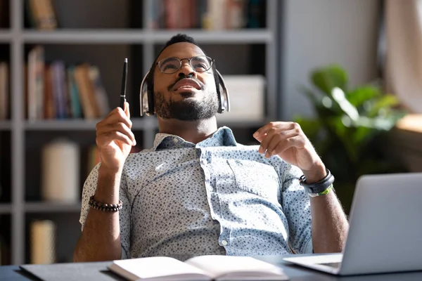 Millennial african businessman wear headphones listening music at workplace — Stock Photo, Image