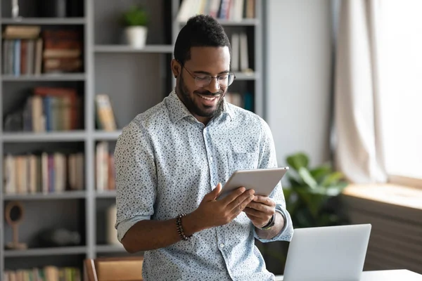Usmívající se africký podnikatel pomocí digitálního tabletu počítače v kanceláři — Stock fotografie