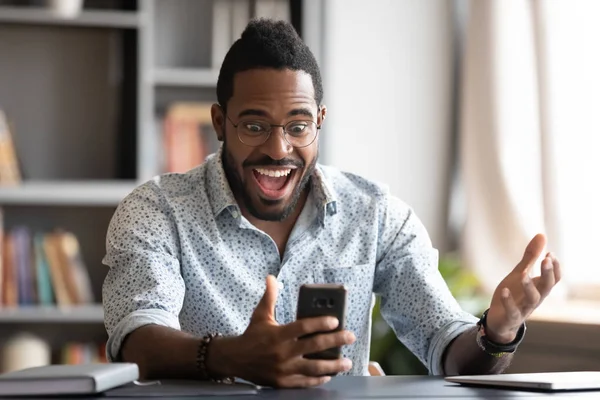 Homem de negócios africano super feliz usando smartphone animado sobre a vitória móvel — Fotografia de Stock