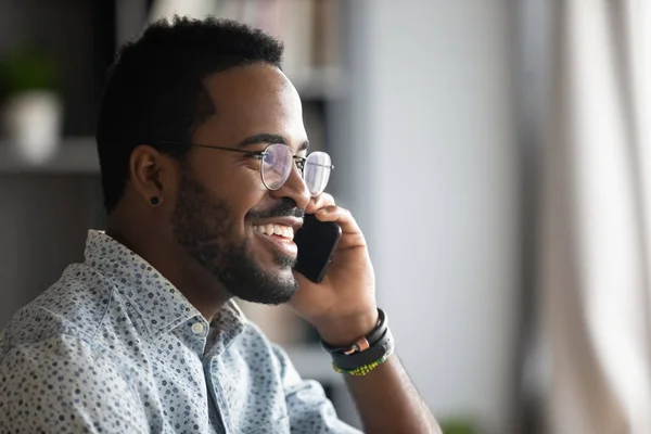 Улыбающийся африканский бизнесмен делает деловой звонок, разговаривая по телефону — стоковое фото