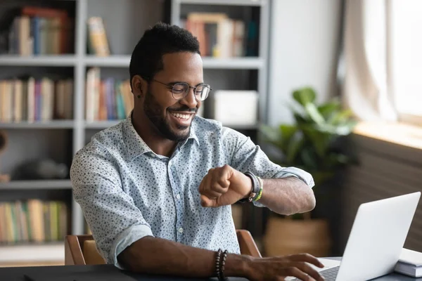 Trabalhador de negócios africano feliz olhando relógio inteligente no trabalho — Fotografia de Stock