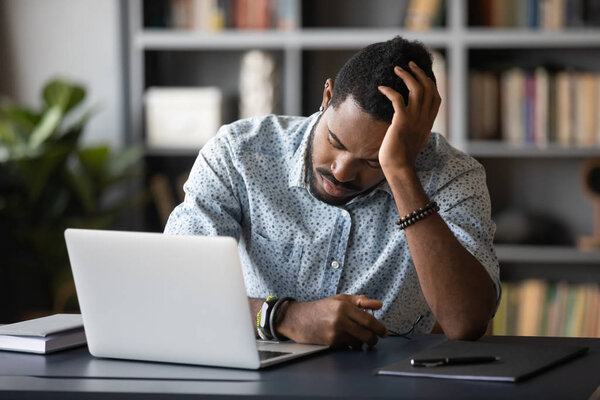 Tired bored african employee falling asleep sitting at work desk