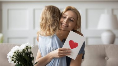 Anne küçük anaokulu kızını kucaklıyor, tebrik ediyor..