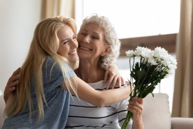Neşeli yetişkin kız, yaşlı anneye sarılıyor..