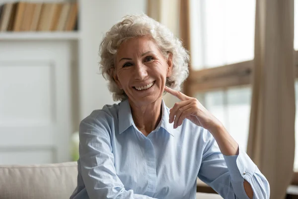 Porträt einer lächelnden alten Frau, die es sich zu Hause auf dem Sofa gemütlich macht. — Stockfoto