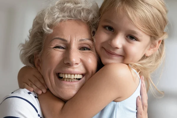 Adorável amorosa menina criança pequena abraçando feliz avó mais velha, retrato . — Fotografia de Stock