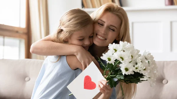 Pequena filha pré-escolar parabenizando mãe sorridente com aniversário . — Fotografia de Stock