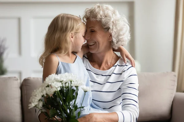 Glücklich liebevolle Oma mittleren Alters rührt Nasen mit Enkelin an. — Stockfoto