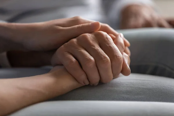 Close-up jonge vrouw houden hand van oudere dame. — Stockfoto