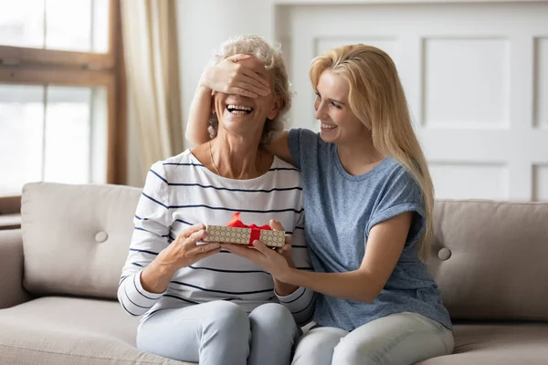 Leende vuxen dotter förberedd överraskning för mor. — Stockfoto